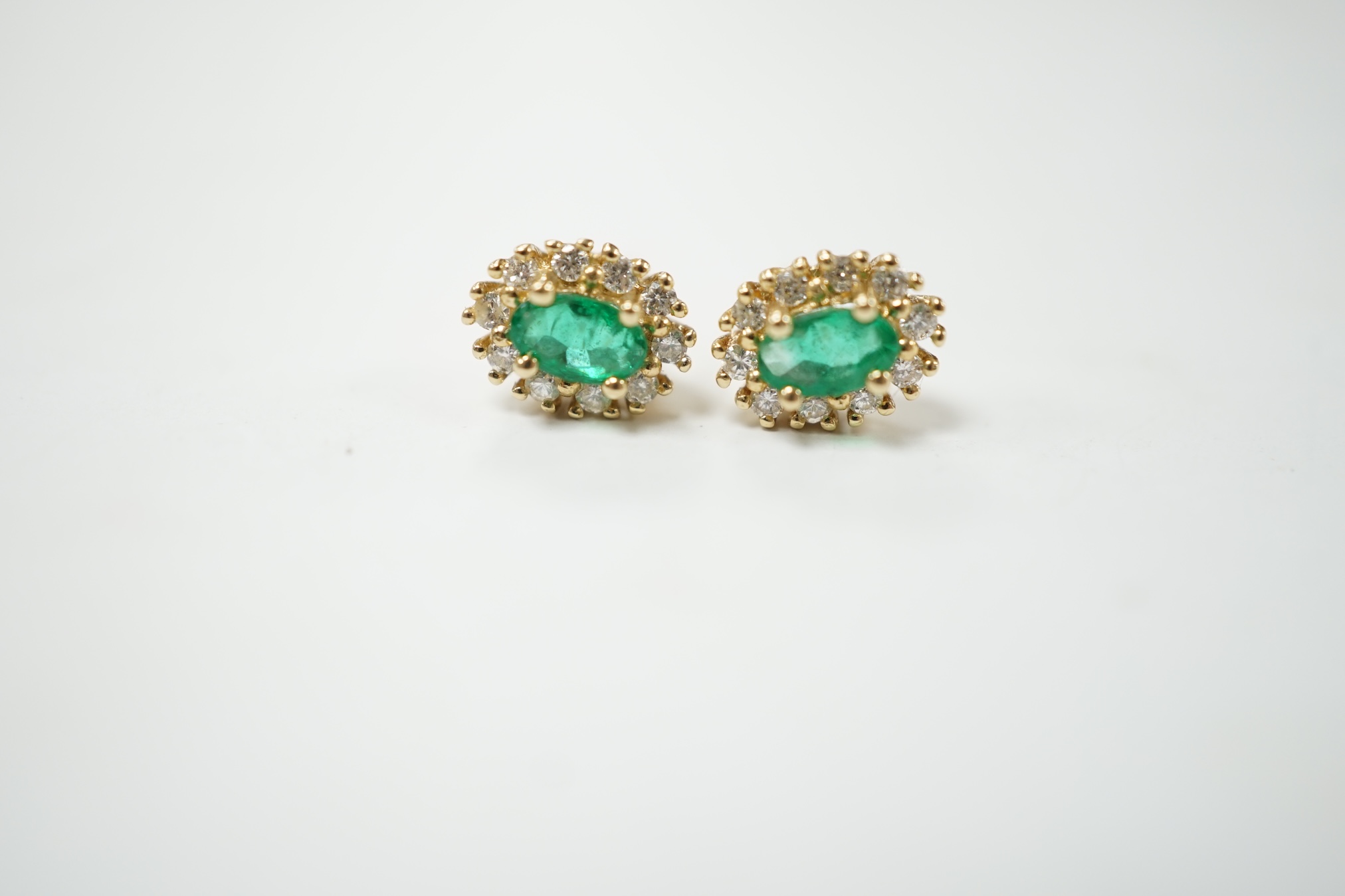 A modern pair of 14k, emerald and diamond set oval cluster ear studs, 8mm, gross weight 1.4 grams. Condition - fair